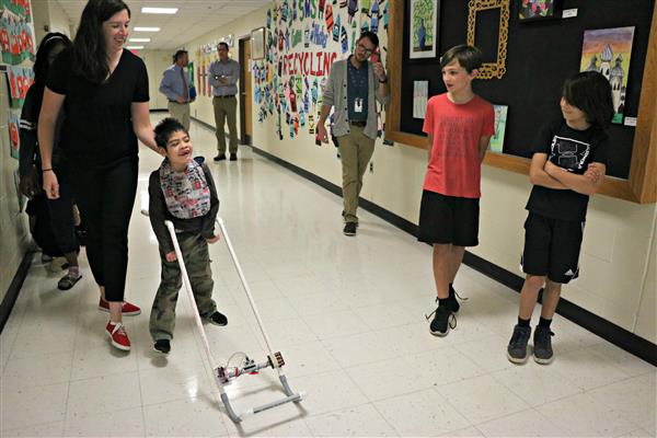 Eli and Will Armbruster watch as Peter Lim tries out wearable cane with sensors. 